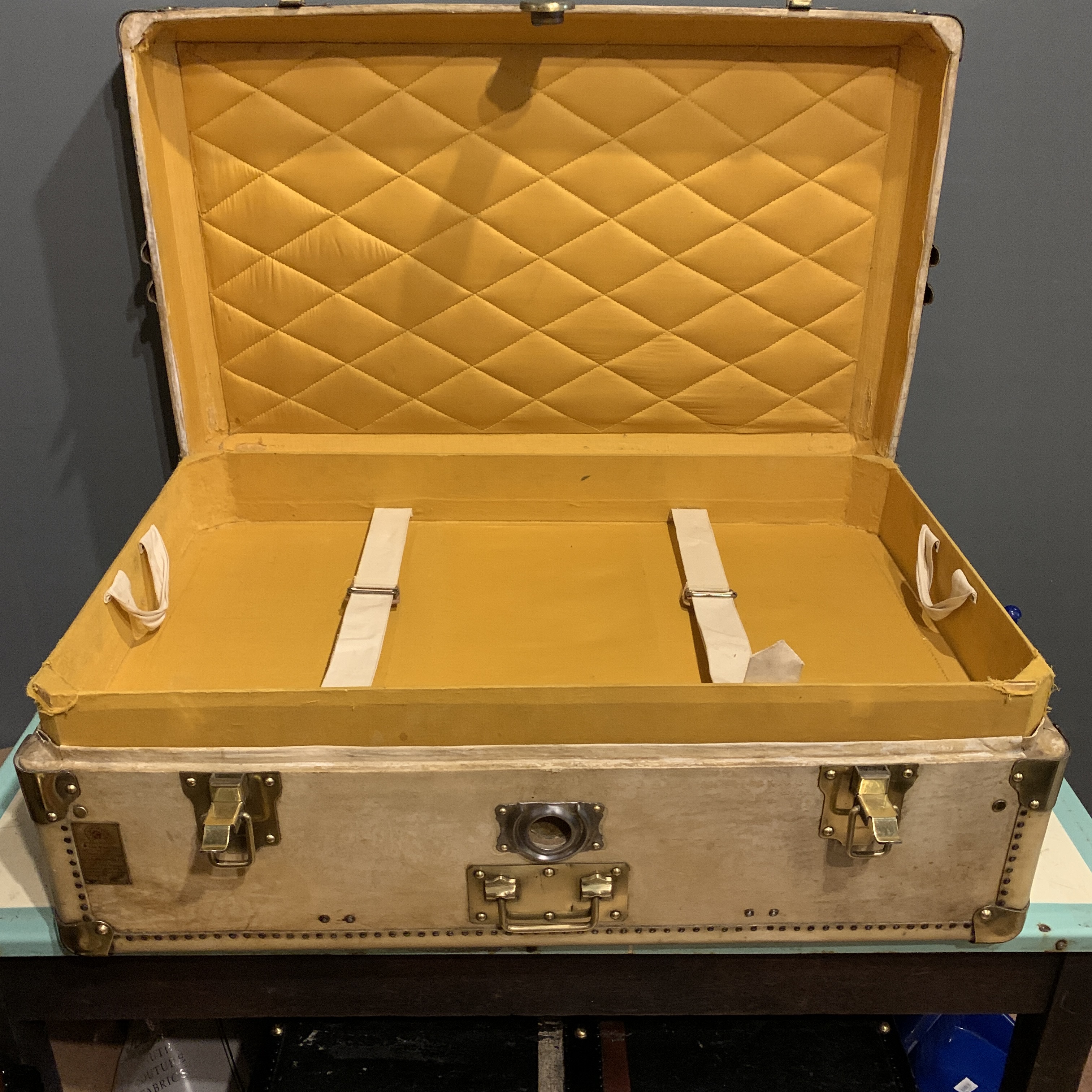 An early 20th century steamer trunk in cream vellum with polished brass locks and trim.